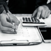 Finance person table's or workplace's close up a shot while he was doing some finance and loan-related work with cell phone, calculator and pages, and pen.